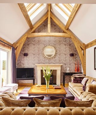 living room showing oak frame structure, vaulted ceiling with rooflight and central fireplace on back wall with patterned wallpaper