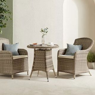 A set of two rattan garden chairs with a bistro table