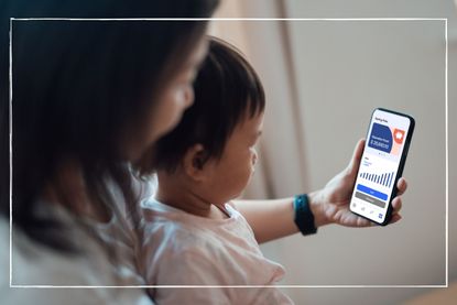 woman with a child on her lap looking at graphs on her phone