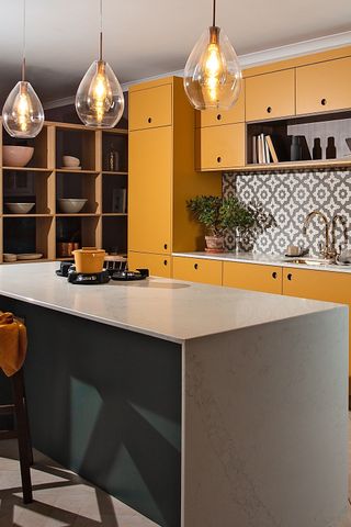 Designing a kitchen island shown in a colorful kitchen with yellow cabinetry, a teal breakfast bar and geometric tiled backsplash.