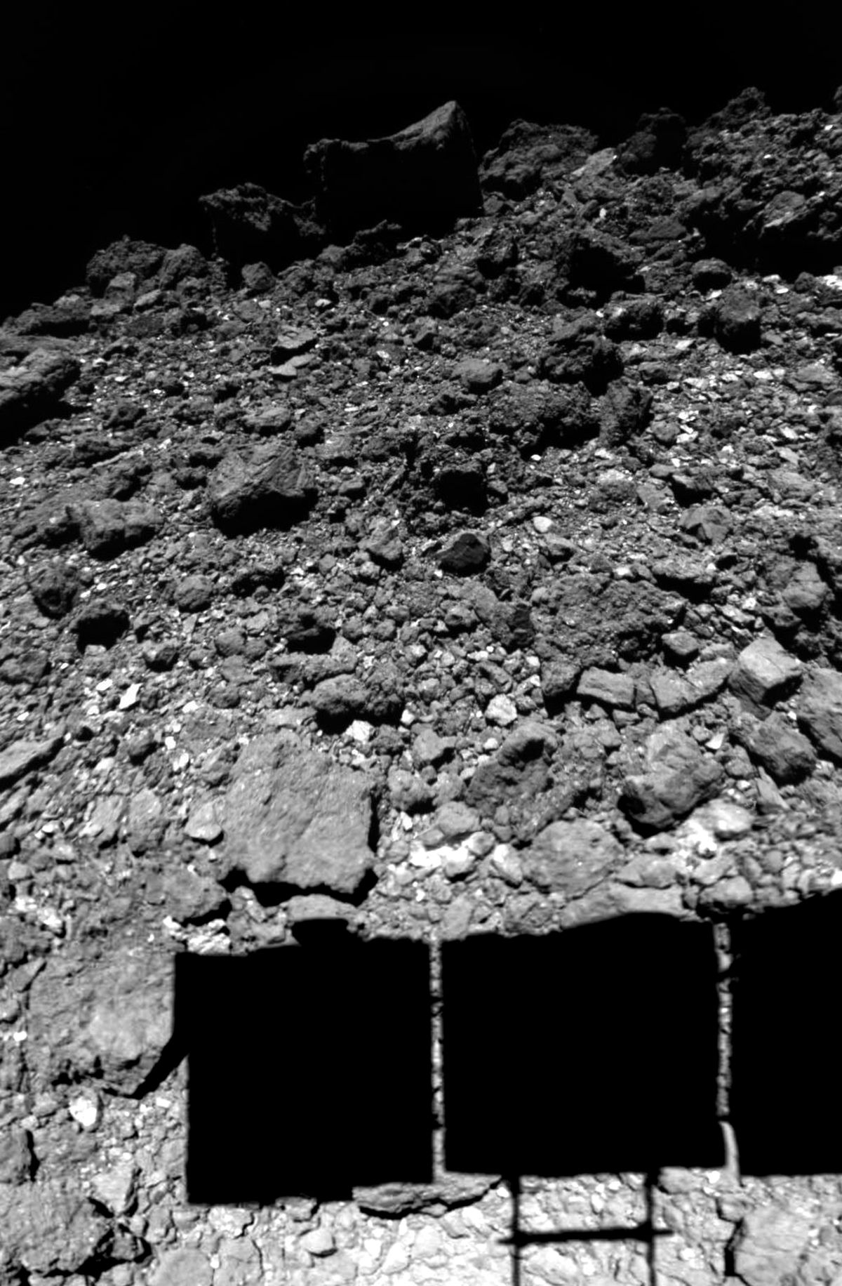 Hayabusa2 casts a shadow on the surface of the asteroid Ryugu during a landing maneuver.