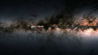 This image shows a section of the side view of the Milky Way as measured by ESA’s Gaia satellite. The dark band consists of gas and dust, which dims the light from the embedded stars. The Galactic Centre of the Milky Way is indicated on the right of the image, shining brightly below the dark zone. The box to the left of the middle marks the location of the “Maggie” gas cloud.