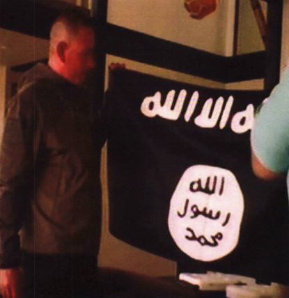 Army Sgt. 1st Class Ikaika Kang holds an Islamic State group flag after allegedly pledging allegiance to the terror group at a house in Honolulu