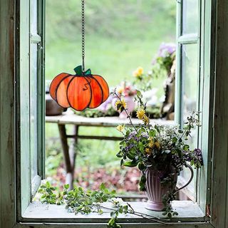 Pumpkin Sun Catcher on a window looking out onto a garden view. 