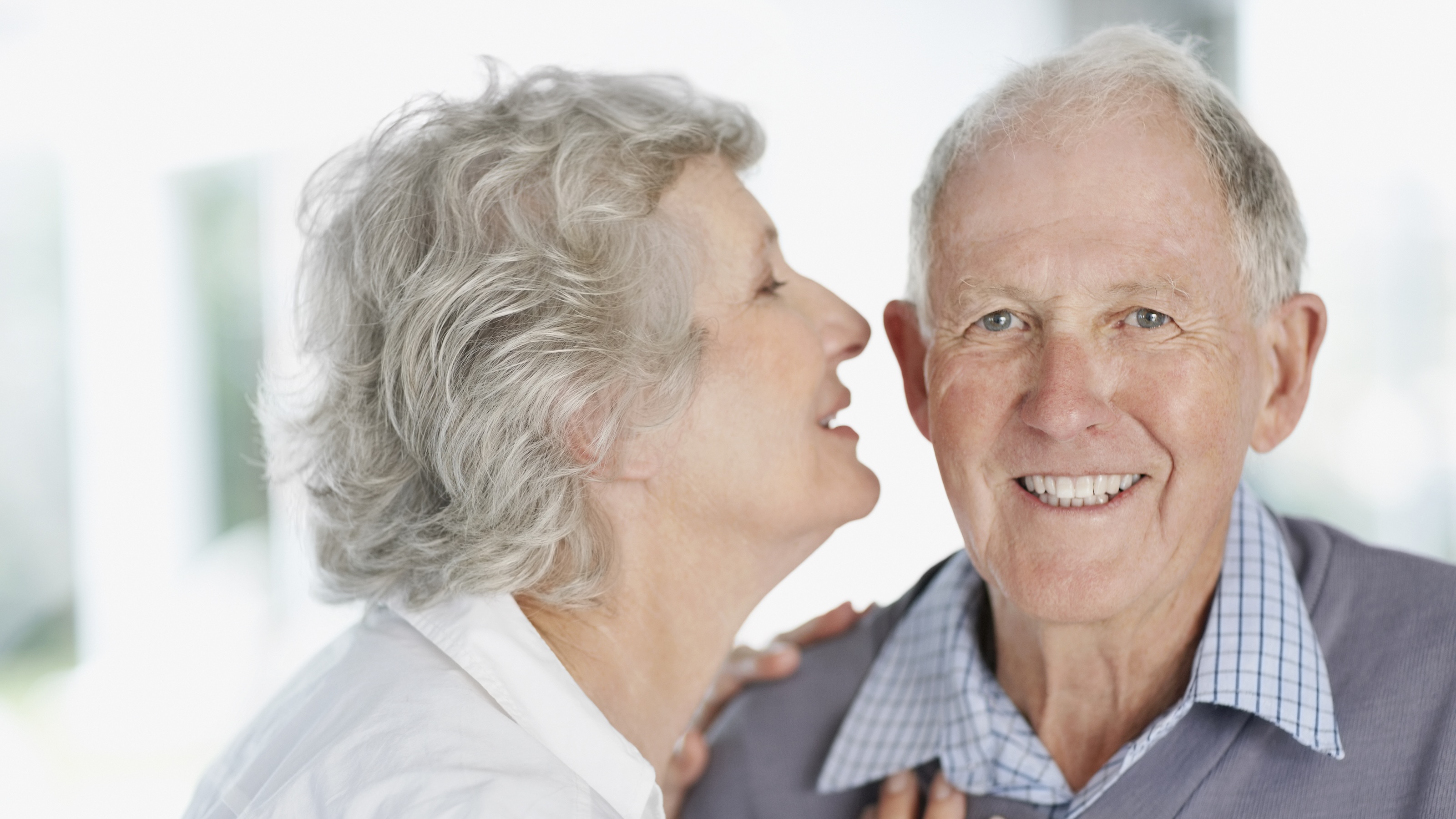 Older woman leaning in to kiss smiling older man