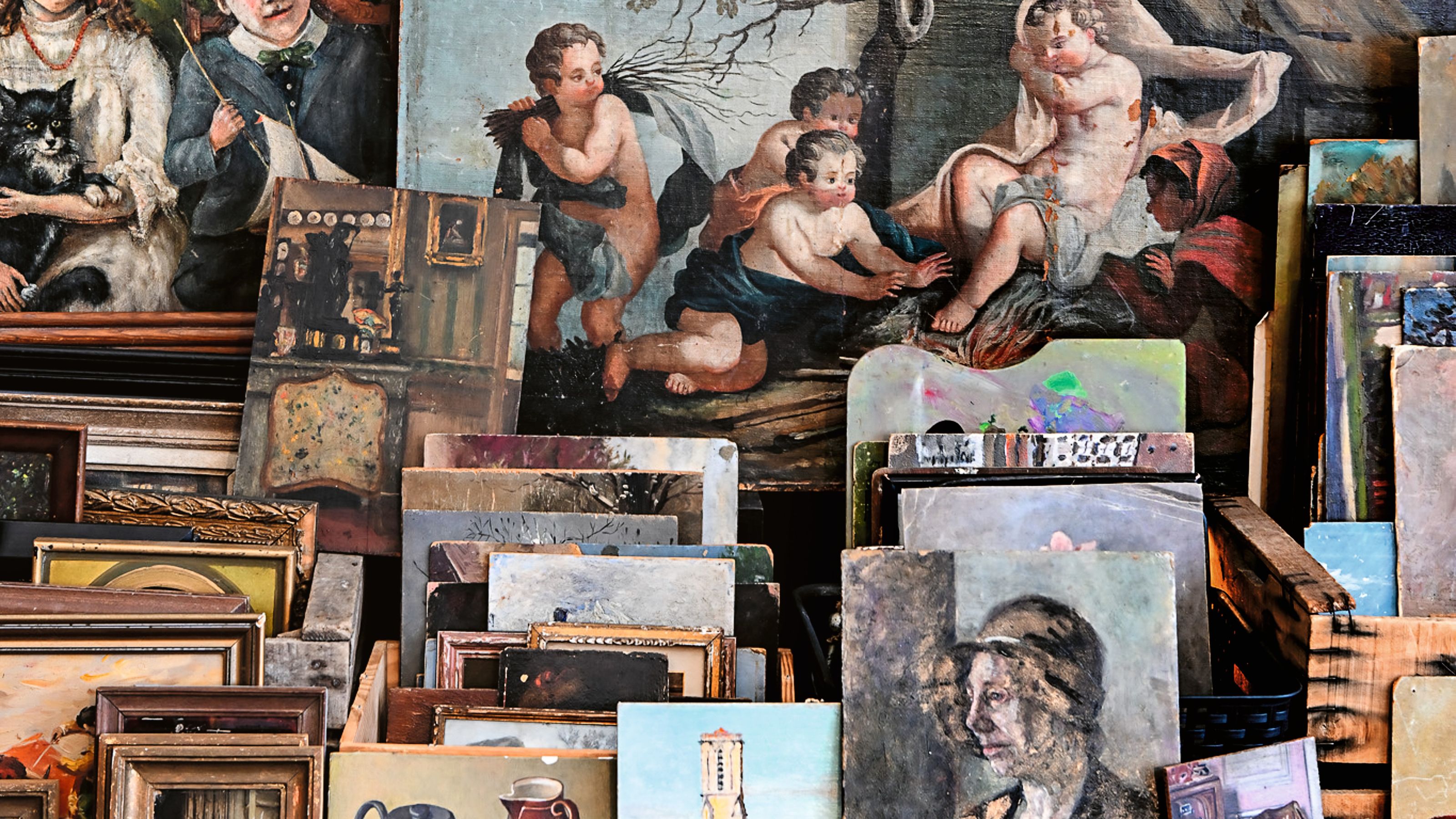 a pile of antique artworks in and out of frames stacked up on the side of the road