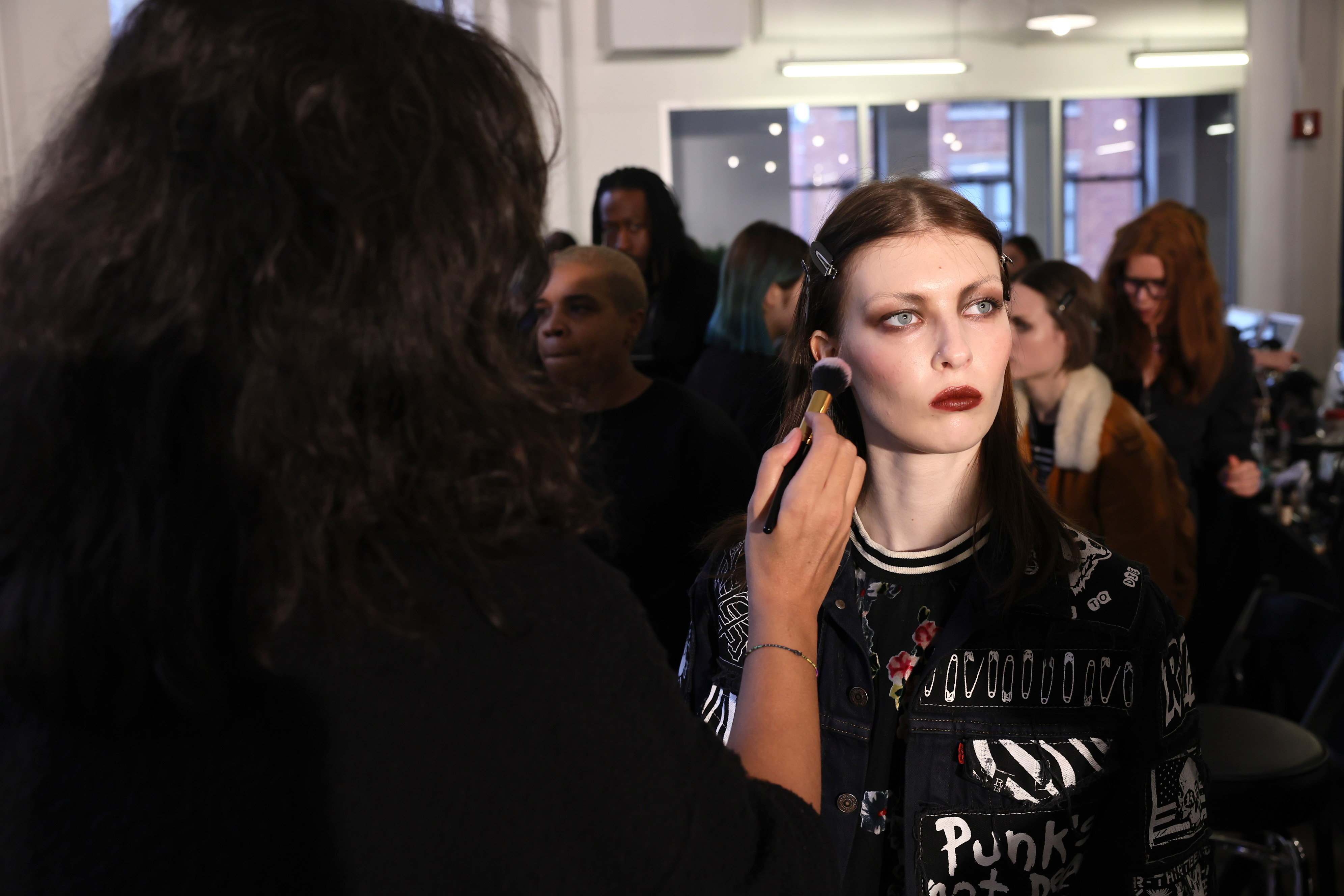 a makeup artist applying makeup to a model backstage at the Anna Sui NYFW 2024 show