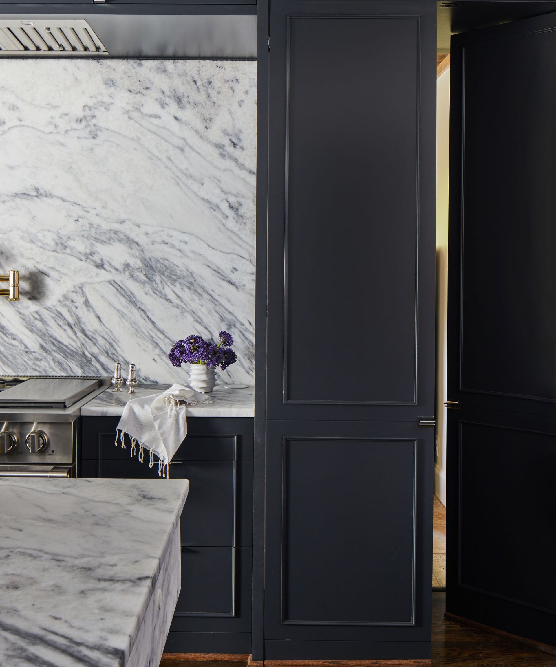 hidden door in dark kitchen cabinets with marble counters