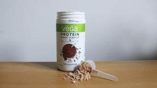 Tub of Vega Protein Made Simple on a table with some powder dispensed