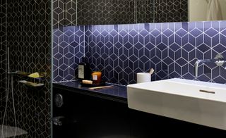 Bathroom interior of sink and dark blue tiled walls