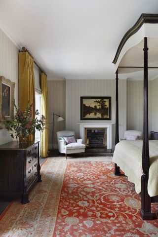 Bedroom with large red patterned rug and four poster bed