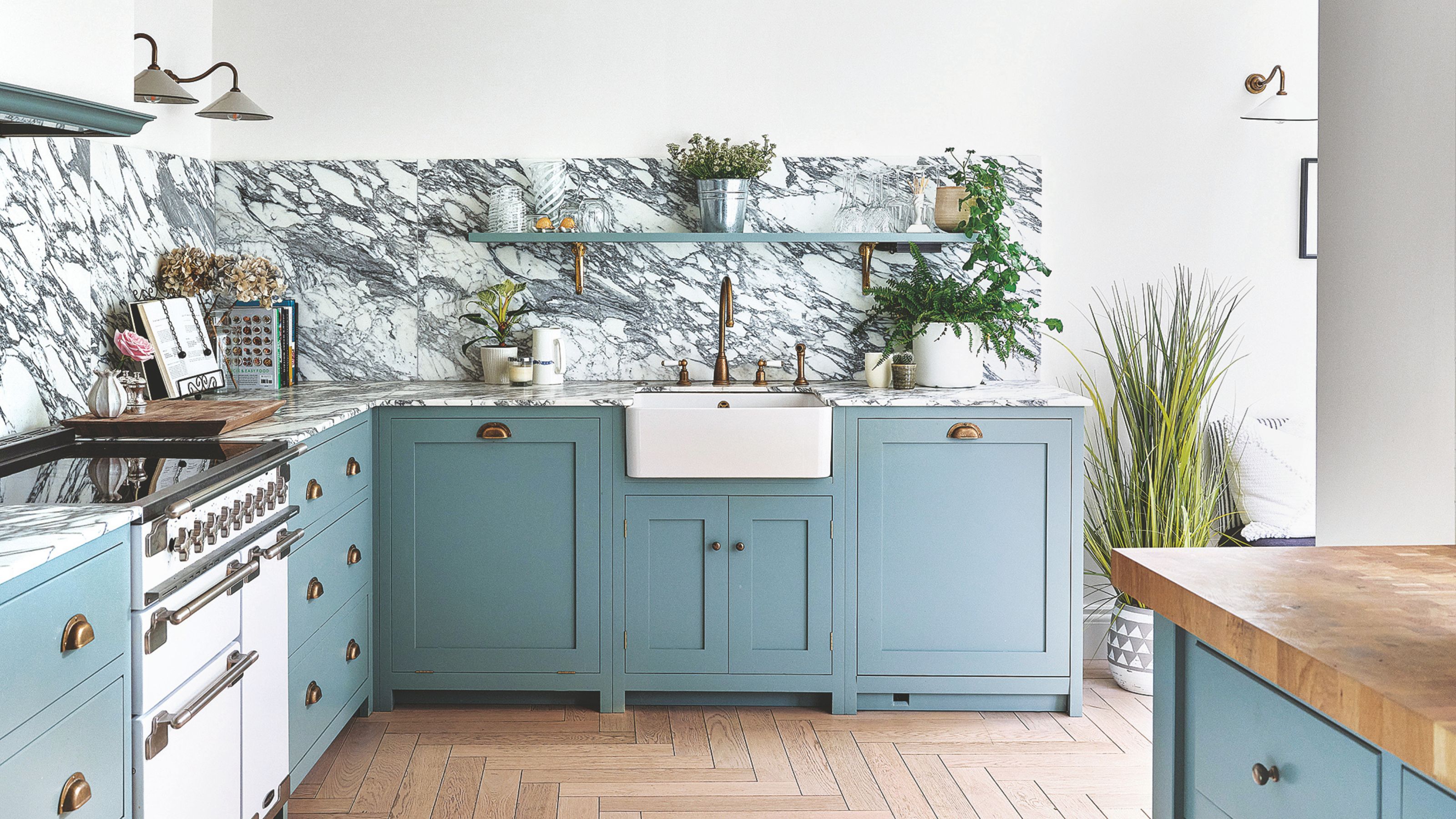 Kitchen with blue cabinets, a marble splashback, wooden floors and white walls 