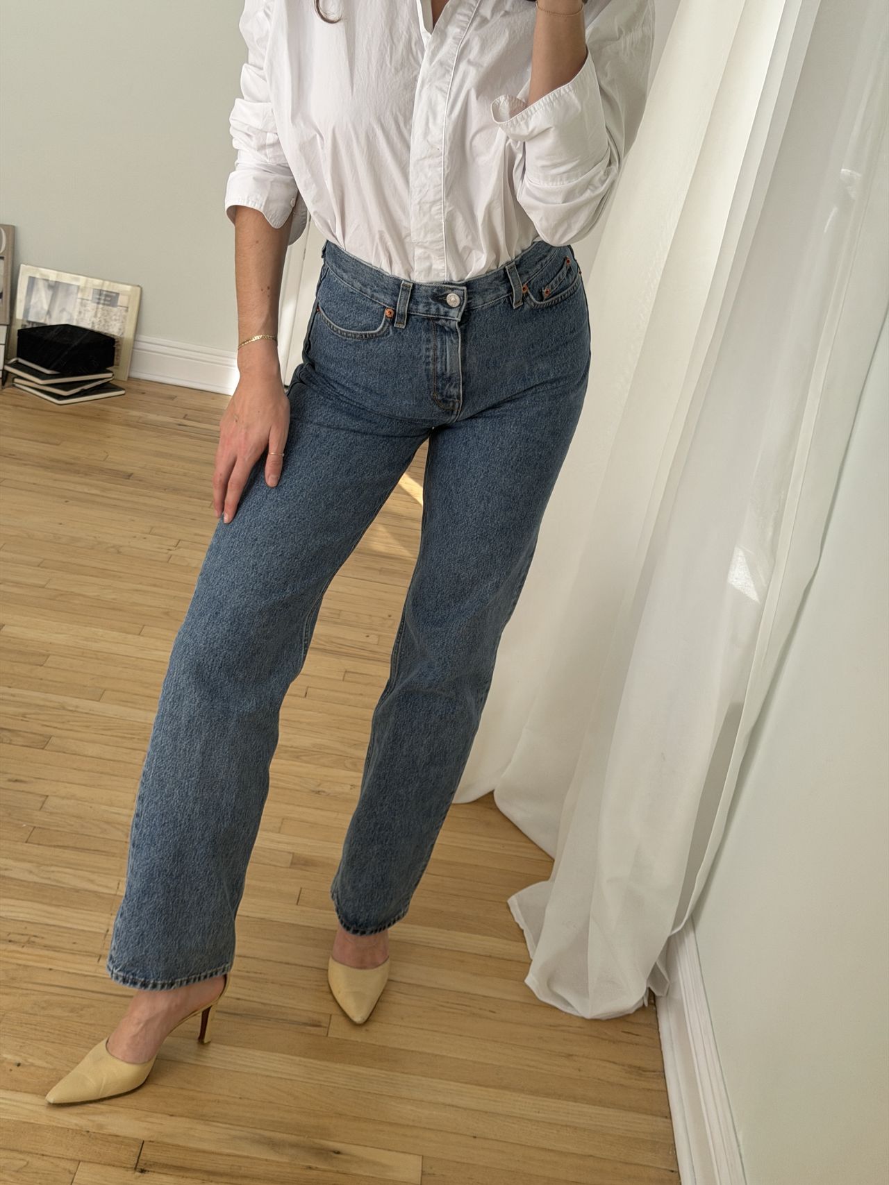 Kathryn Zahorak posing in mirror wearing white button-down shirt, jeans, and heels