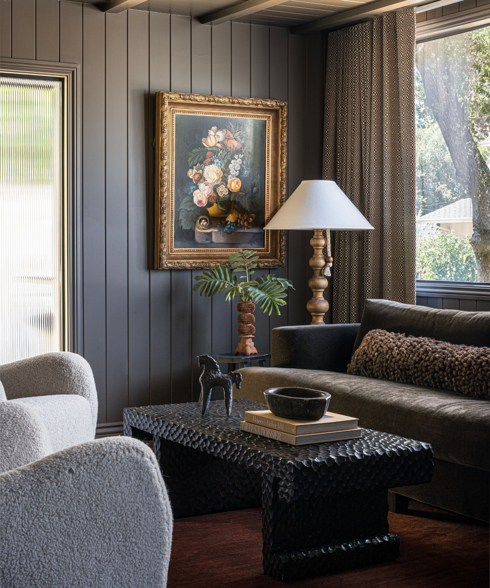 a moody brown paneled snug room with large glass windows and vintage furnishings