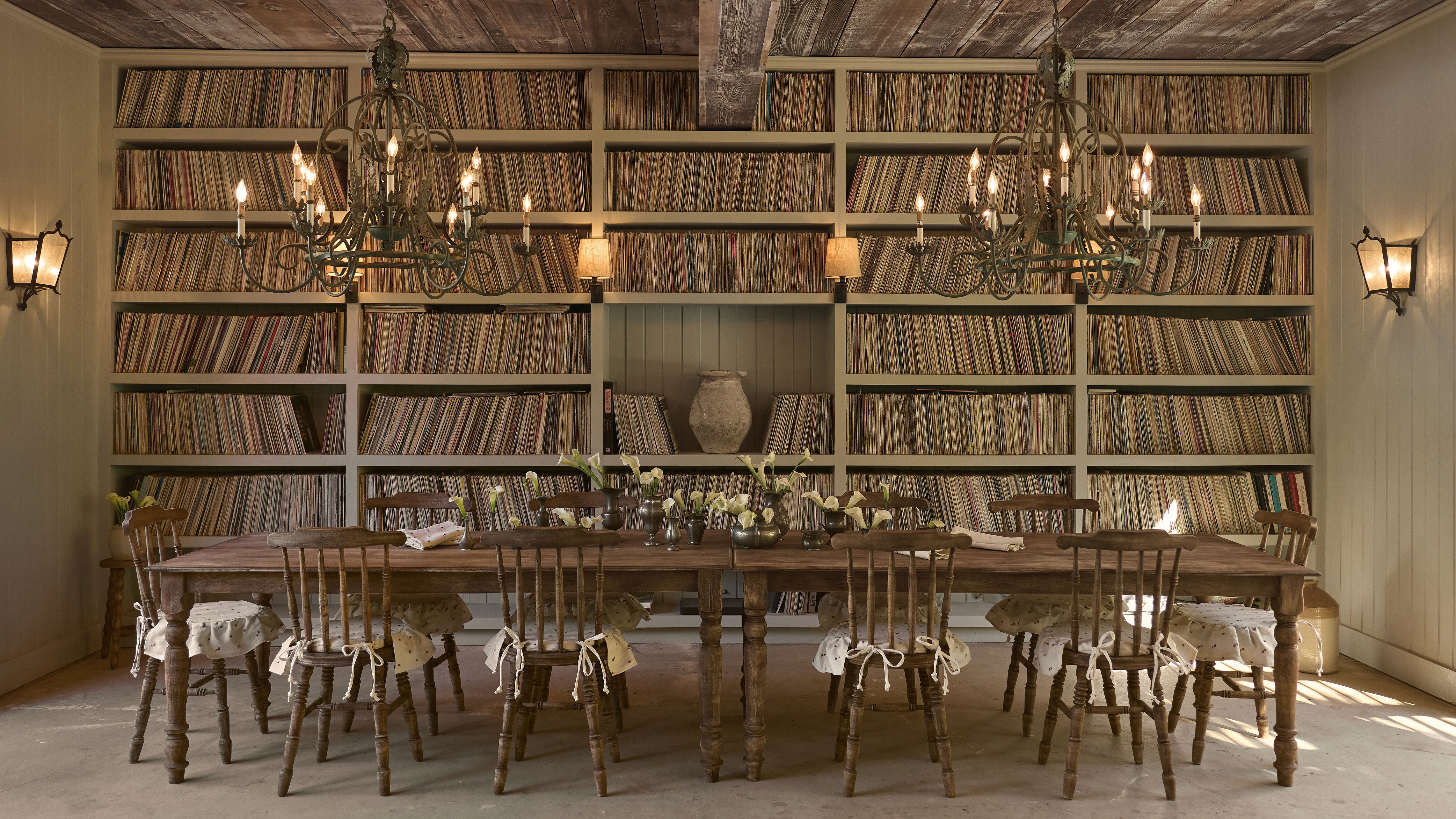 Olive Ateliers&#039; first-ever home furnishings collection, inspired by antique French farmhouse interiors. shot inside of a high-ceilinged dining room with many books