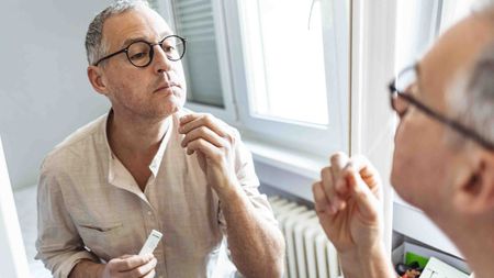 Man looking in the mirror as he gives himself a COVID test