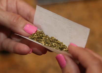 A woman rolls a marijuana cigarette.