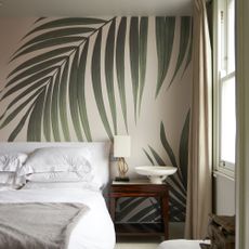 Palm leaf mural behind white bed