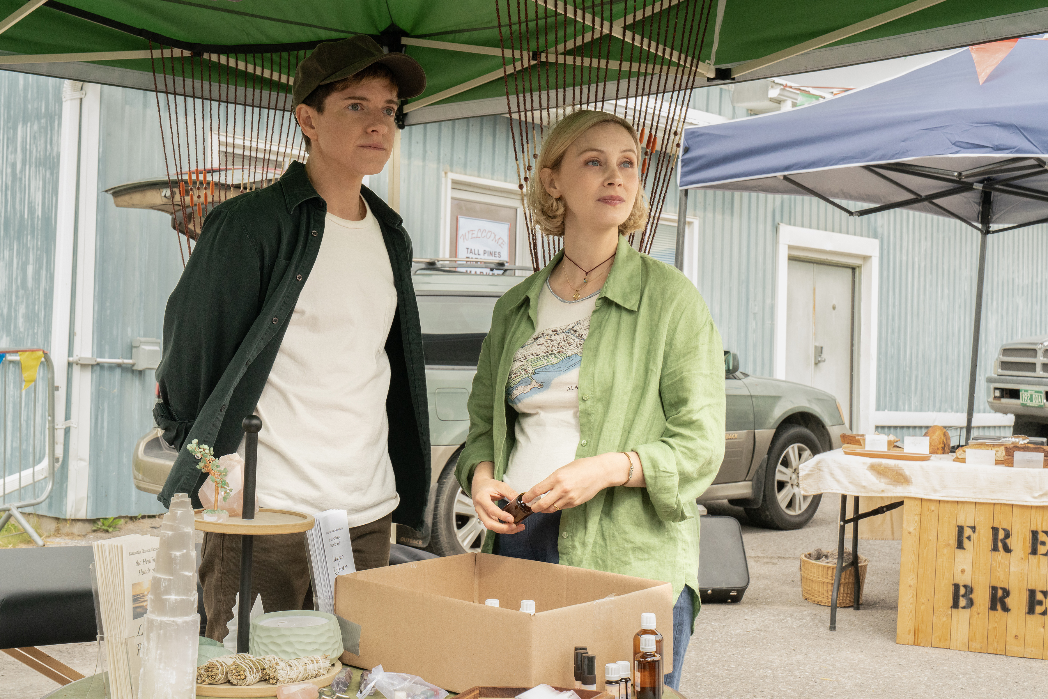 Mae Martin as Alex Dempsey and Sarah Gadon as a couple at a farmers market in wayward