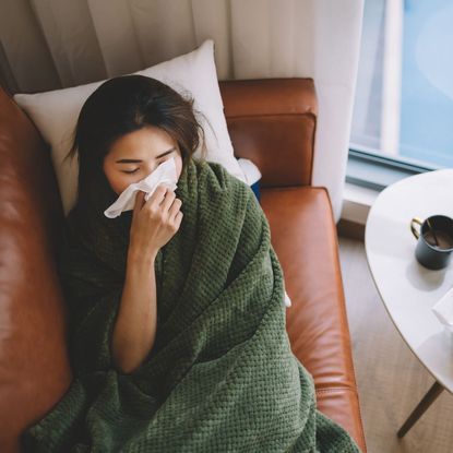 A woman with a cold lying on the sofa ill