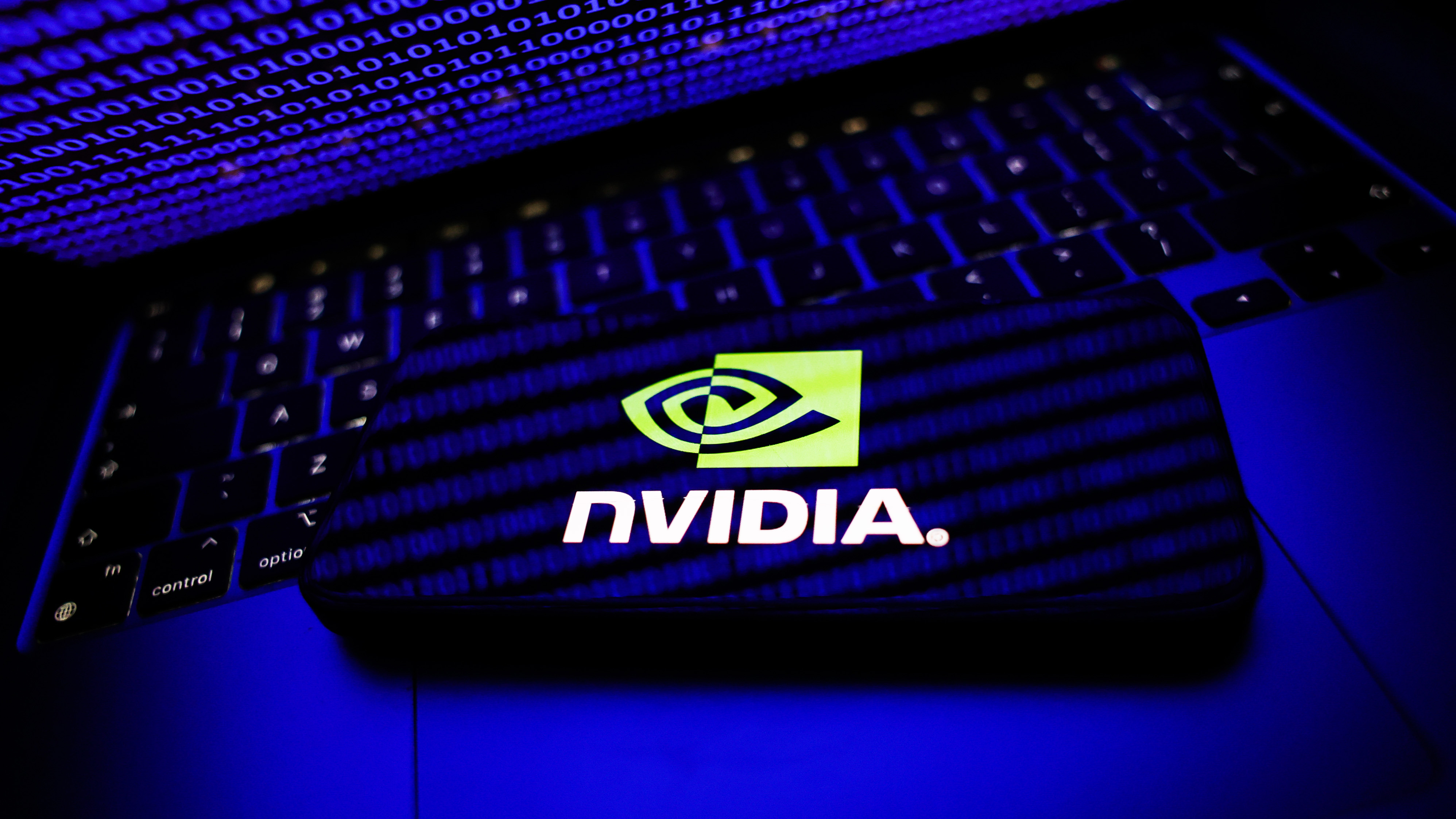 Binary code displayed on a laptop screen displayed on a laptop screen and Nvidia logo displayed on a phone screen are seen in this illustration photo taken in Krakow, Poland on August 8, 2025. (Photo by Jakub Porzycki/NurPhoto via Getty Images)