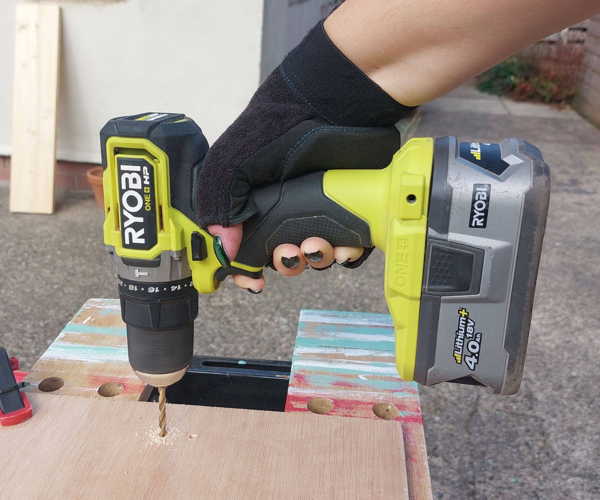 A compact cordless drill boring a hole into a piece of wood