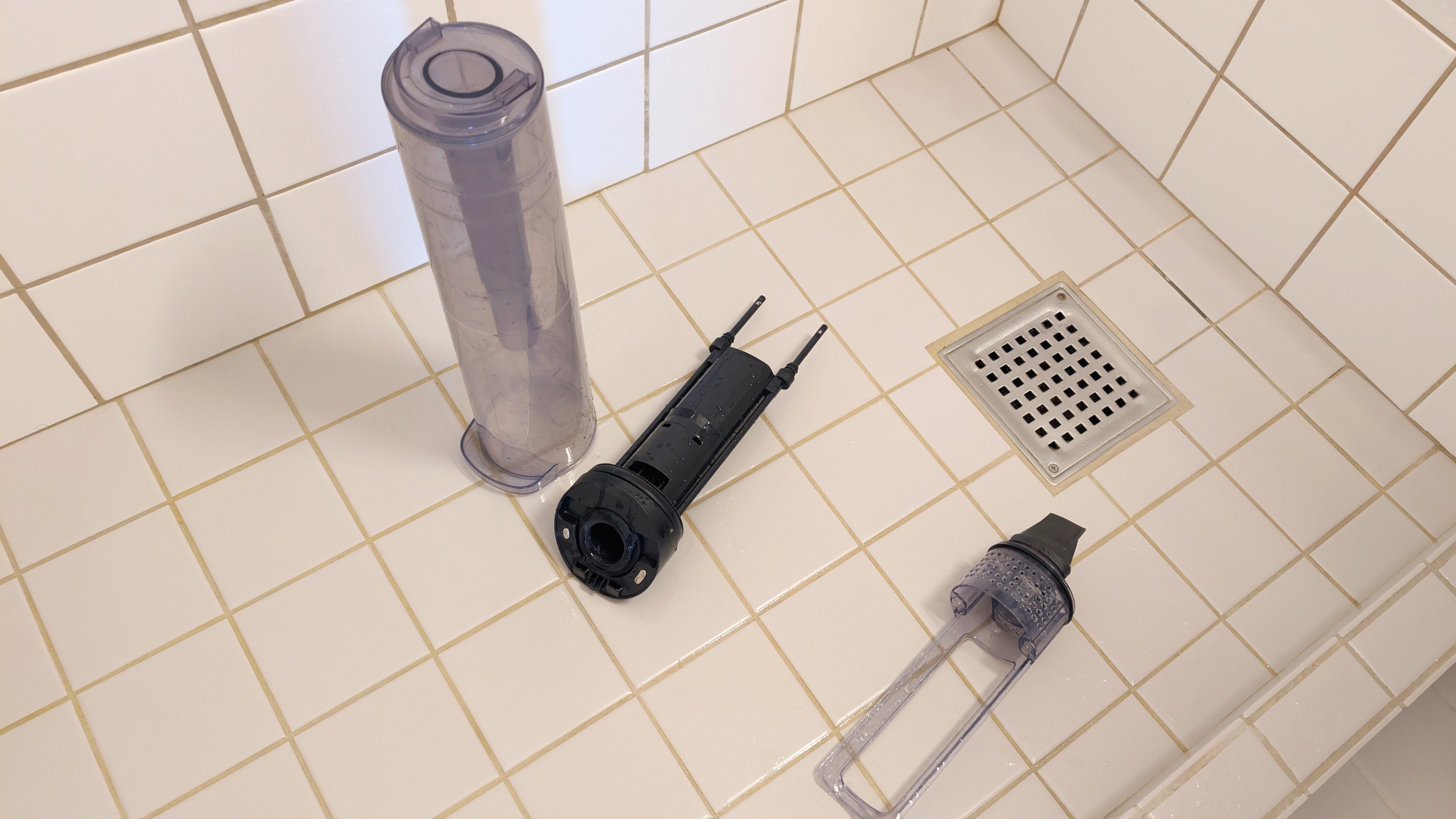 Spildevandsbeholder og filtre fra Electrolux 800 Wet&amp;amp;Dry ligger p&amp;aring; gulvet i brusenichen.