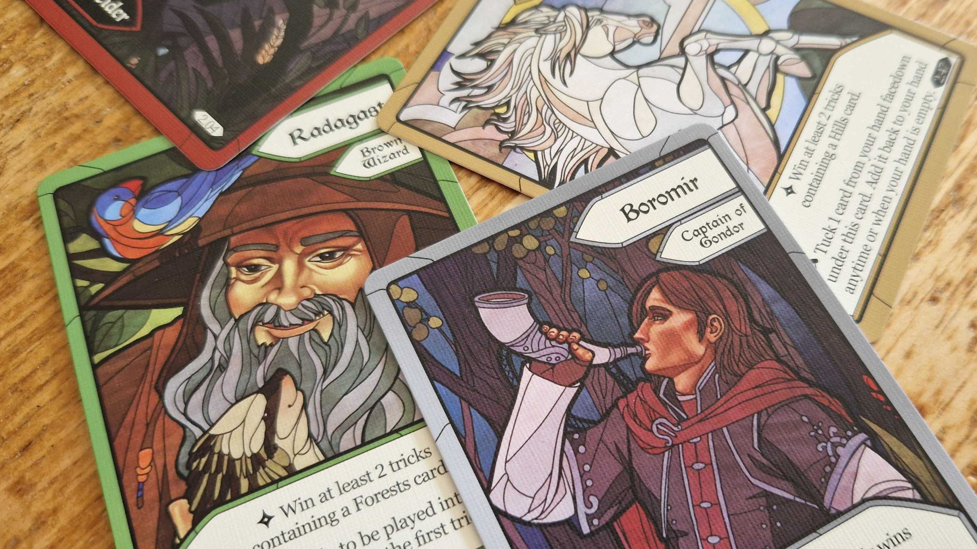 A handful of cards depicting characters from The Lord of the Rings on a wooden surface