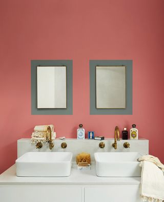 pink bathroom walls and two sinks with grey painted around the mirrors
