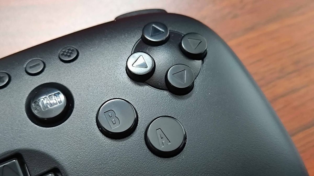 Close up of 8Bitdo N64 Bluetooth controller right hand buttings sitting on woodgrain surface.