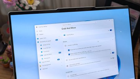 A laptop screen displaying Windows 11, featuring the "Grab And Move" settings window of PowerToys. The desktop background is colorful and vibrant.