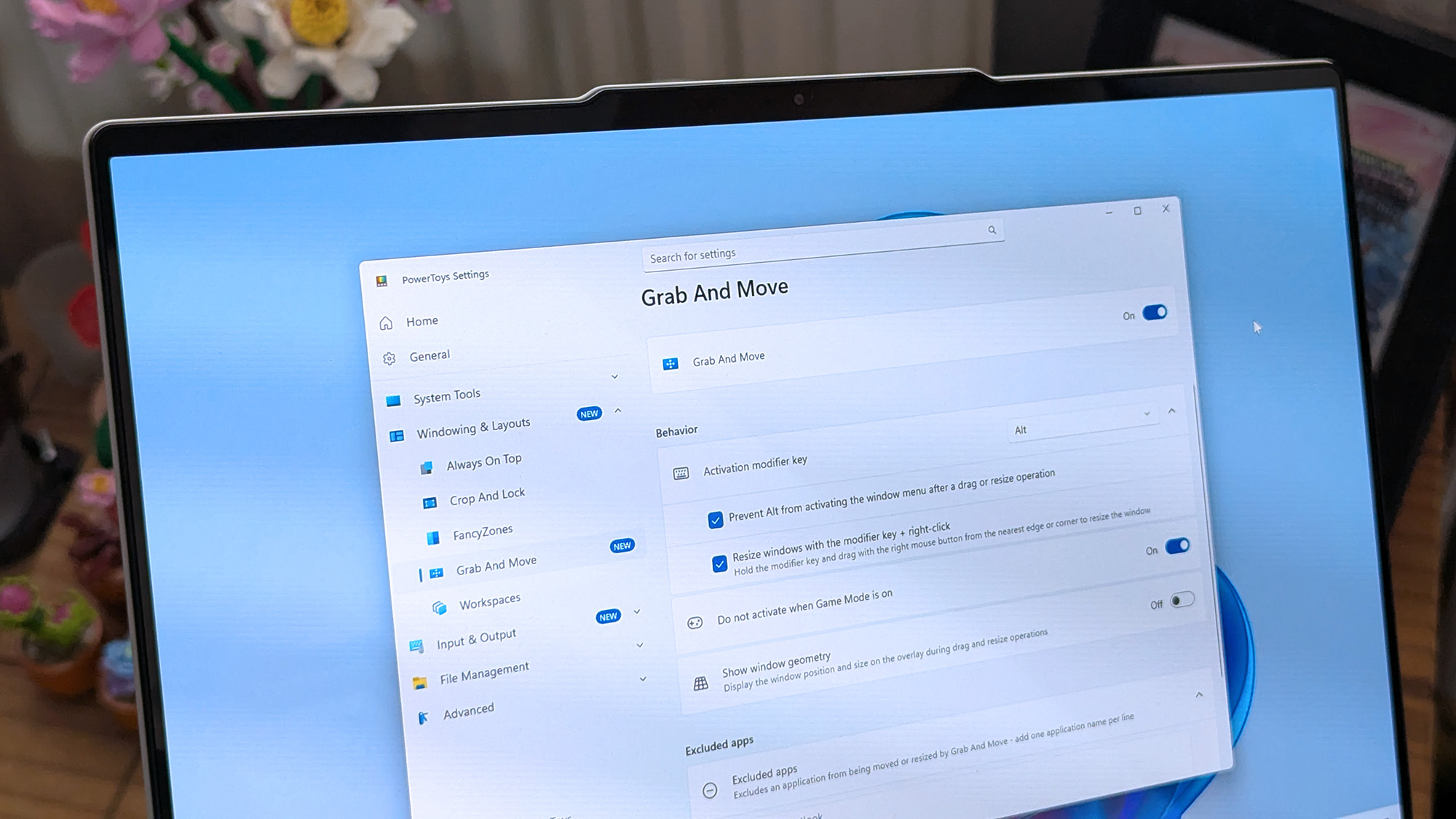 A laptop screen displaying Windows 11, featuring the "Grab And Move" settings window of PowerToys. The desktop background is colorful and vibrant.
