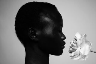 Black and white photo of a person with short hair and a white flower