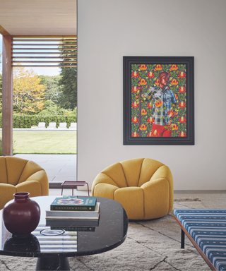 seating area in hamptons house yellow modern armchairs with artwork coffee table and vase and rug and books