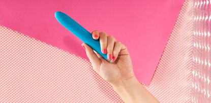 Young Woman Holding Vibrator against pink backdrop