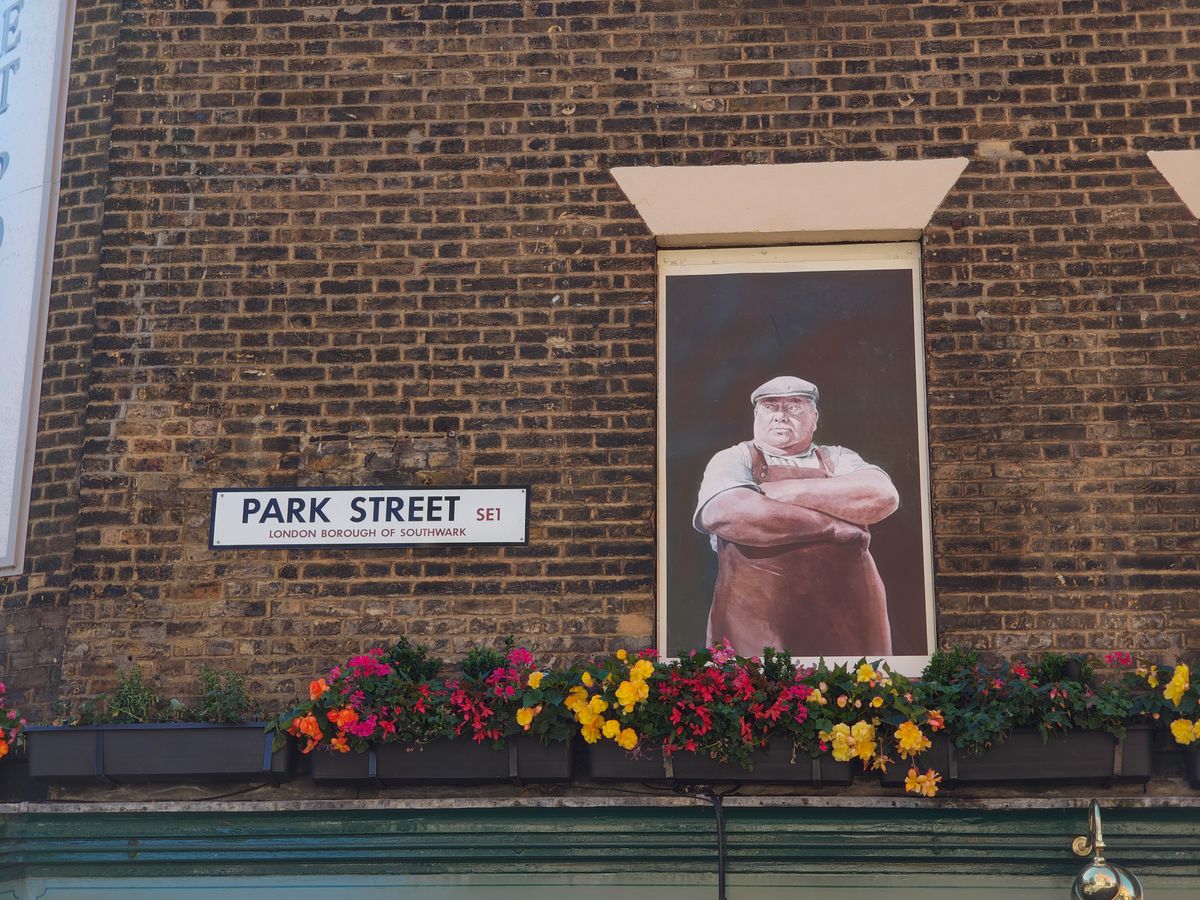 A street sign in London next to a mural of a butcher