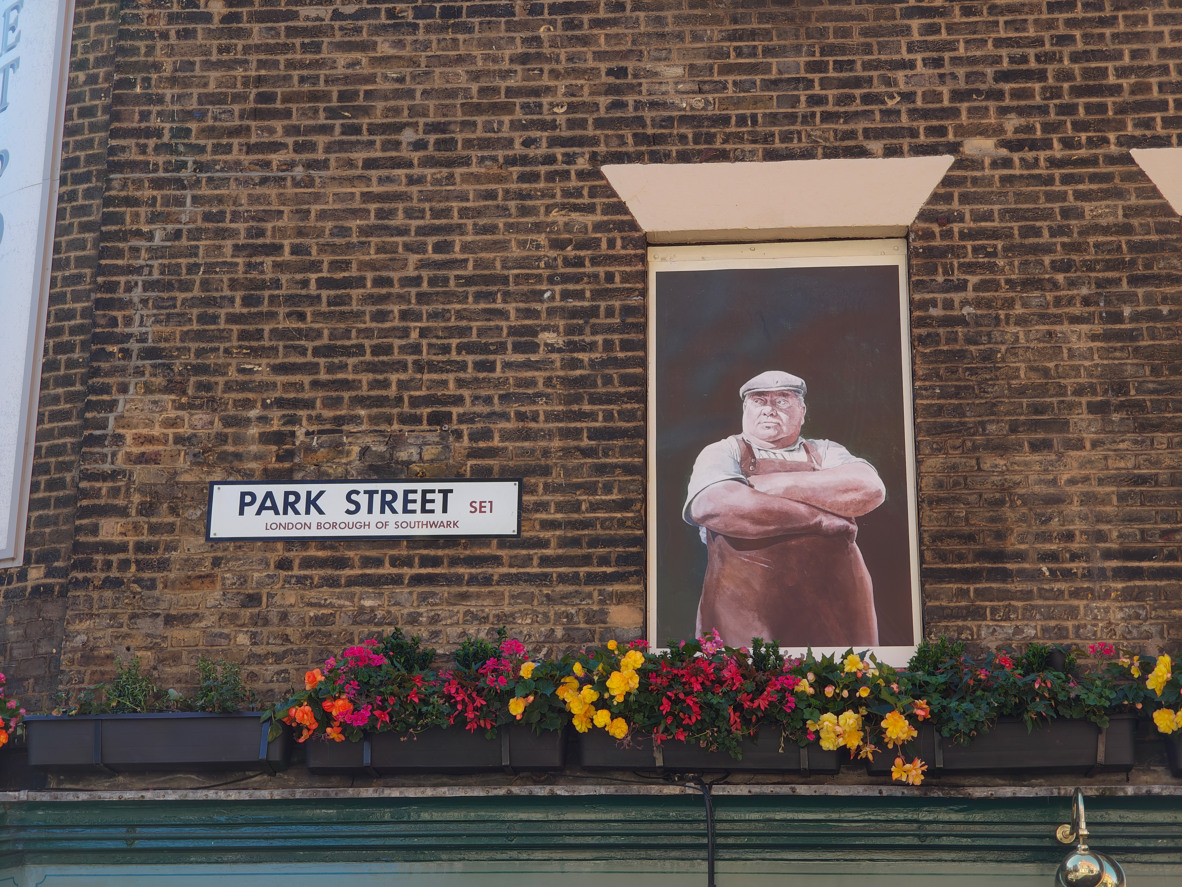 A street sign in London next to a mural of a butcher