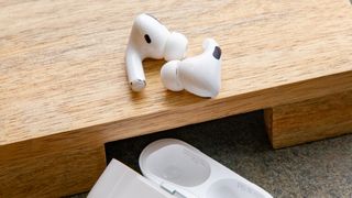 Die AirPods Pro auf einer hölzernen Oberfläche neben ihrem Ladecase platziert