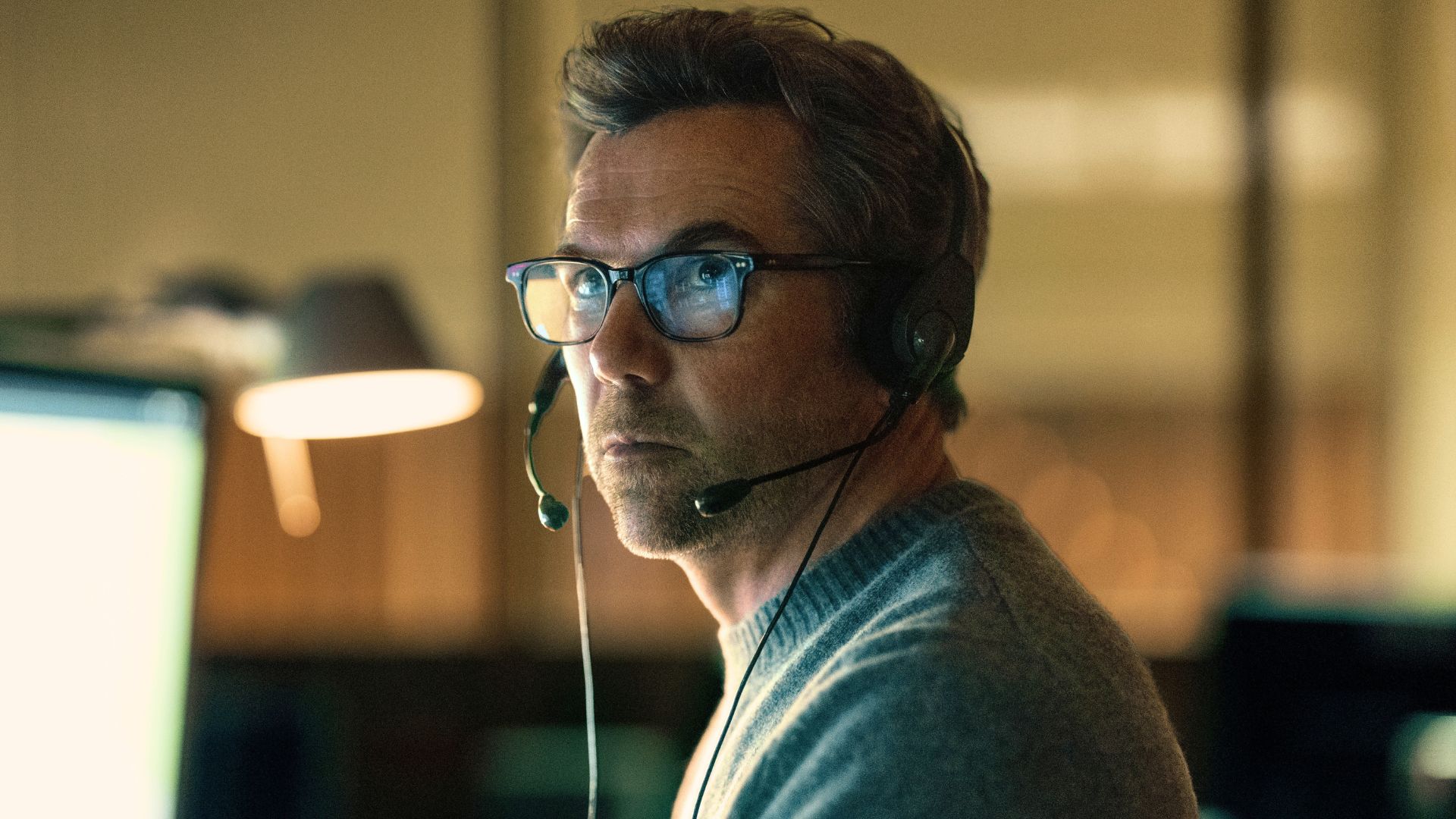 Ian looks at a computer screen while wearing a headset