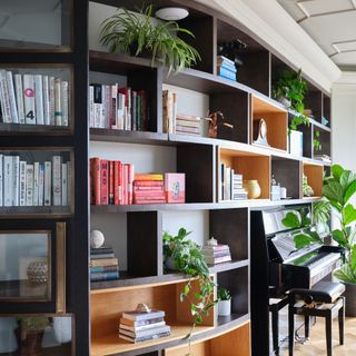 Bookshelves in a living room with a piano and houseplants