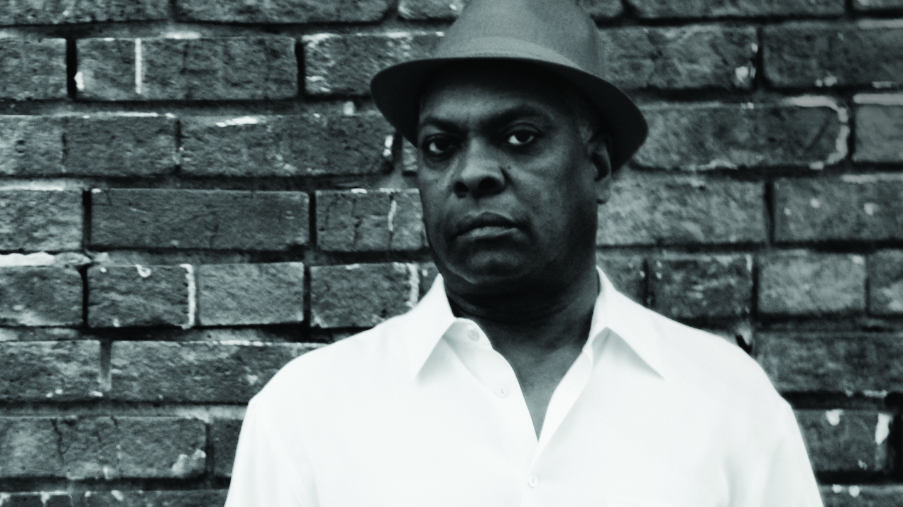 Booker T Jones standing in front of a brick wall.