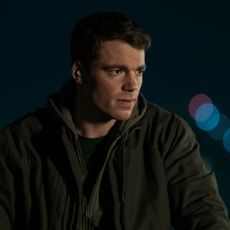 gabriel basso as peter sutherland wearing a jacket outside at nighttime in a still from the night agent season 2