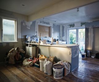 kitchen extension mid-decoration with plastic covering floor and worktops and build materials stacked on floor