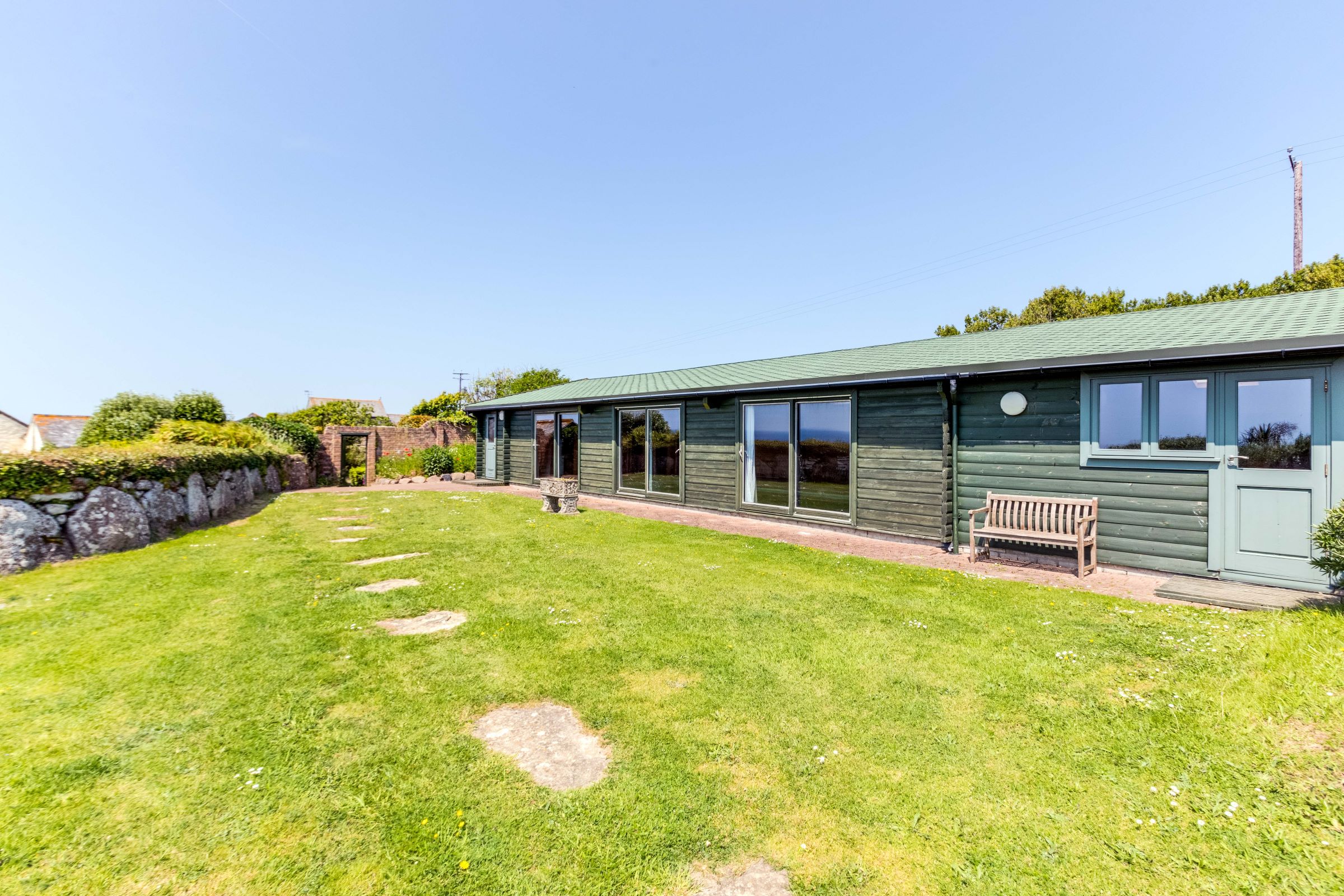 Wooden outbuildings in the garden, which are long and has a pool inside