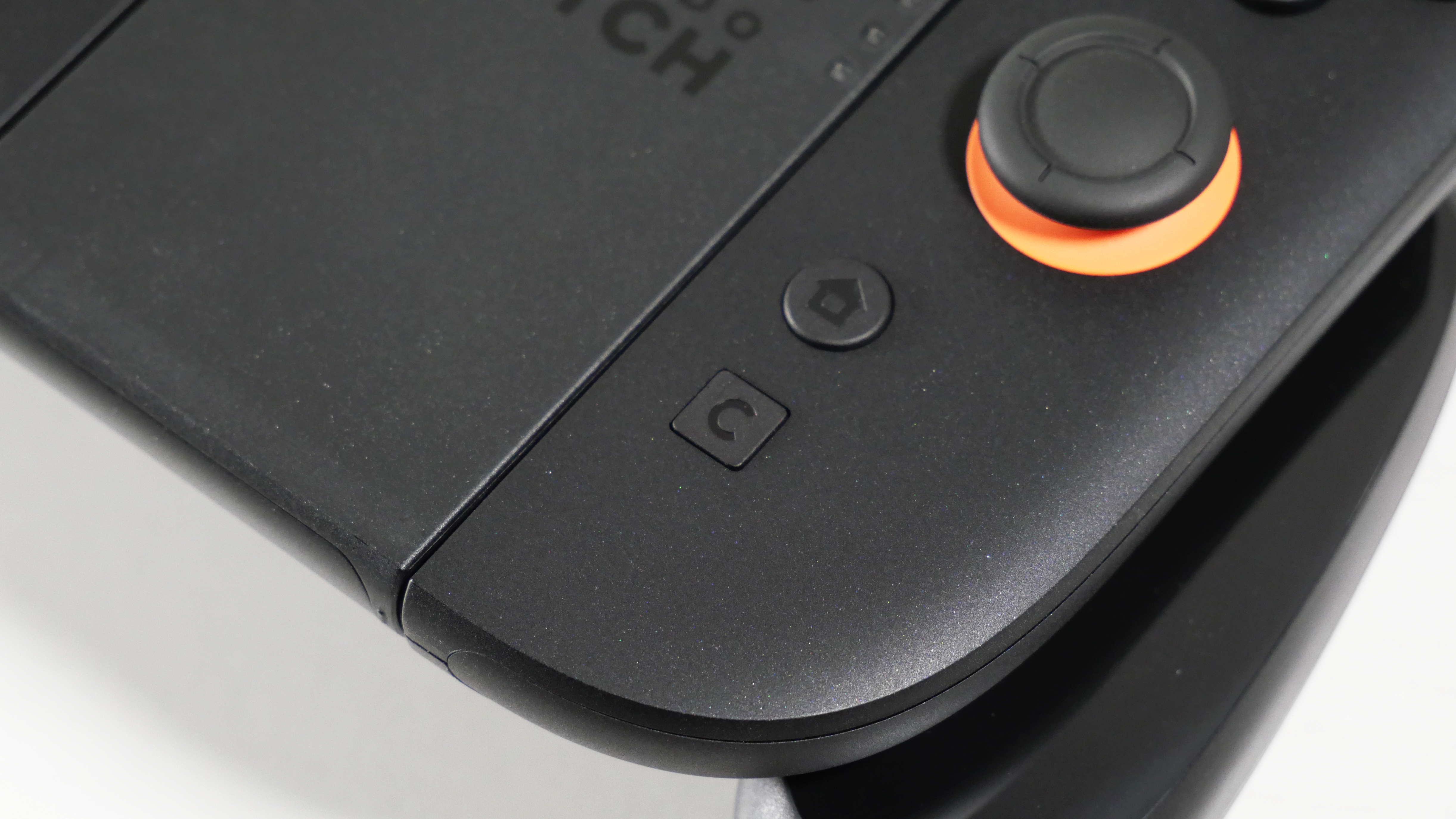Nintendo Switch 2 Joy-Con 2 Grip laying on a white desk, highlighting its C button.