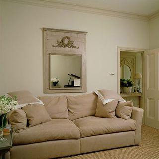living room with mirror and cream coloured sofa and cushions