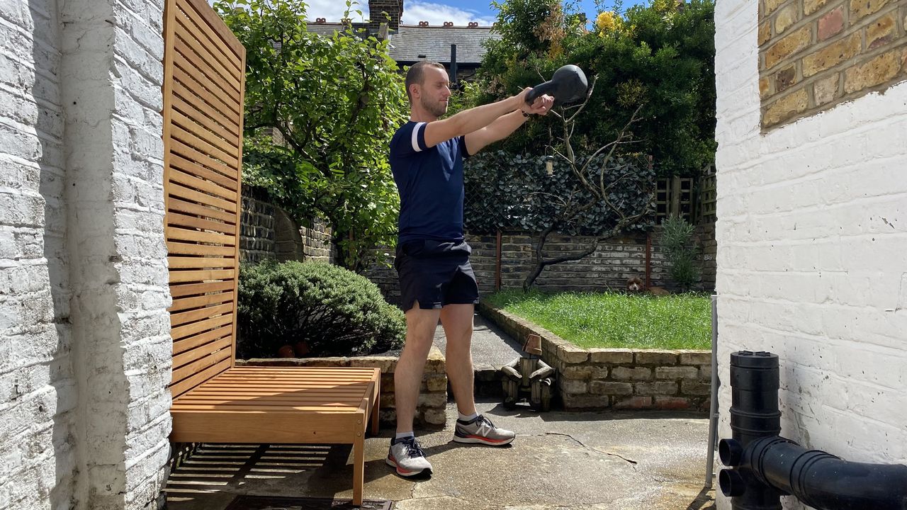 Man doing kettlebell swings outside