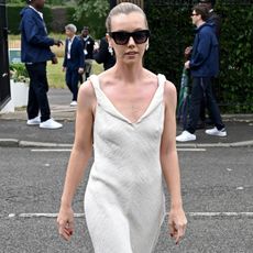 A guest at Wimbledon wears a pair of white pointed-toe shoes and a cream dress to the tournament