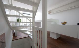 The kitchen and dining area captured from under the white stairs. On the right is the white island with a white walled shelf above