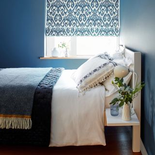 blue bedroom with wooden bend and patterned blinds